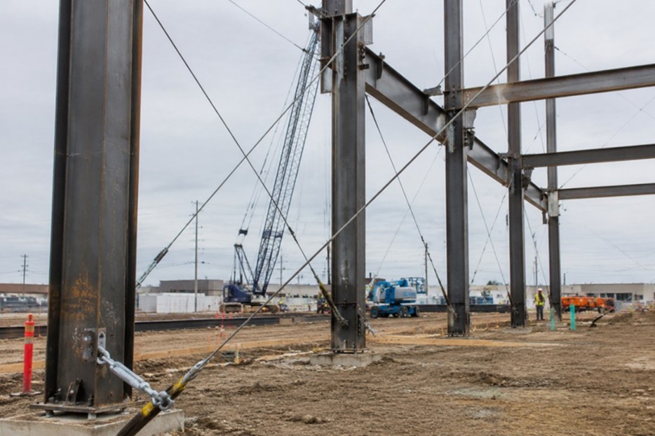 Structure under construction with temporary bracing and crane operations